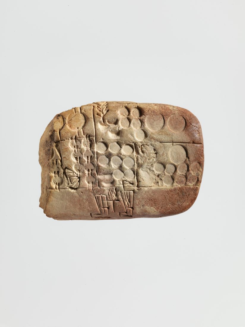 A baked clay tablet packed with small wedge-shaped marks, photographed so the dents look physical.