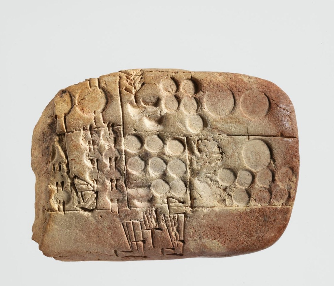 A baked clay tablet packed with small wedge-shaped marks, photographed so the dents look physical.