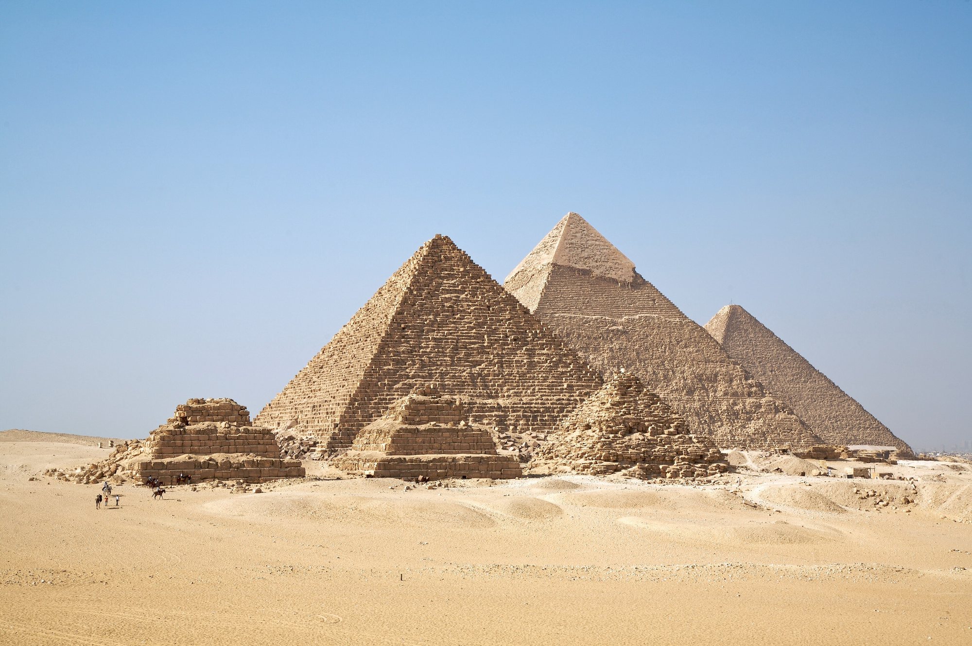 The three pyramids of Giza standing on the desert plateau under a wide sky.